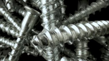 Siyah arka planda dönen çelik krom vidalar yığını. Paslanmaz çelik cıvatalar, masada demir cıvatalar. Helix ipliği, süper makro yakın plan. Yavaş çekim hazır 59.97fps.