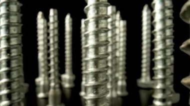 Metal vidalar, paslanmaz cıvatalar, siyah arka planda dönen vidalı çelik demirler. Tamir etmek, tamir etmek, düzmek için spiral yapı malzemeleri. Kapatın. Yavaş çekim hazır 59.97fps.
