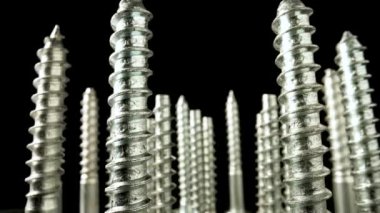 Metal vidalar, paslanmaz cıvatalar, siyah arka planda dönen vidalı çelik demirler. Tamir etmek, tamir etmek, düzmek için spiral yapı malzemeleri. Kapatın. Yavaş çekim hazır 59.97fps.