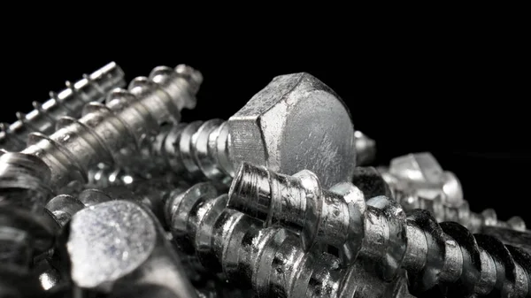 Çelik krom vida yığını. Paslanmaz çelik cıvatalar, masada demir cıvatalar. Metalik sarmal oymacılık. Makro, kapat..