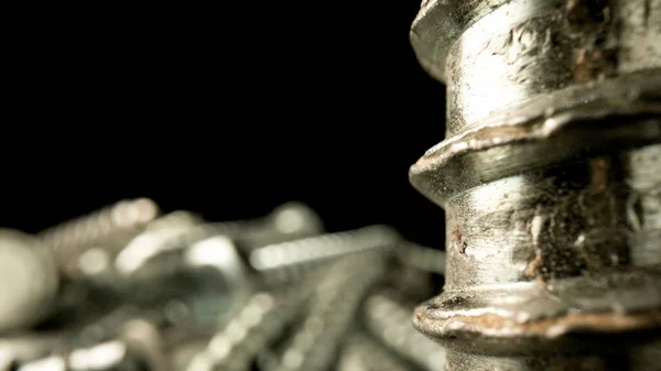スチールクロムネジの山。ステンレス製のボルト、テーブルの上の金属アンカーボルト。金属ヘリカル彫刻の関節。マクロを閉じる. — ストック写真