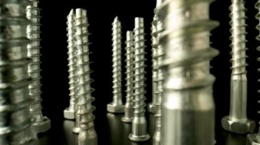 Vidalar, metal işlemeli cıvatalar, izole edilmiş siyah arka planda dönen bağlayıcılar. Çelik krom sunucu bir atölyede ya da hırdavatçıda vidalanır. Süper makro yakın çekim. Yavaş çekim hazır 59.97fps.