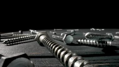 Kamera vidaları, metal başlıklı cıvataları, siyah arka planda duran bağlayıcıları kapatıyor. Çelik krom sunucu bir atölyede ya da hırdavatçıda vidalanır. Süper makro yakın çekim. Yavaş çekim hazır 59.97fps