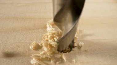 Tahtayı delme matkabının ayrıntıları. Ahşap yüzey deliniyor, talaş uçuyor. Yavaş çekimde dönen metal matkap. İnşaat ve onarım, ahşap işçiliği, marangozluk. Kapat..