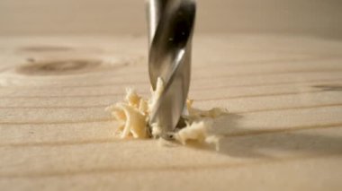 Tahtayı delme matkabının ayrıntıları. Ahşap yüzey deliniyor, talaş uçuyor. Yavaş çekimde dönen metal matkap. İnşaat ve onarım, ahşap işçiliği, marangozluk. Kapat..