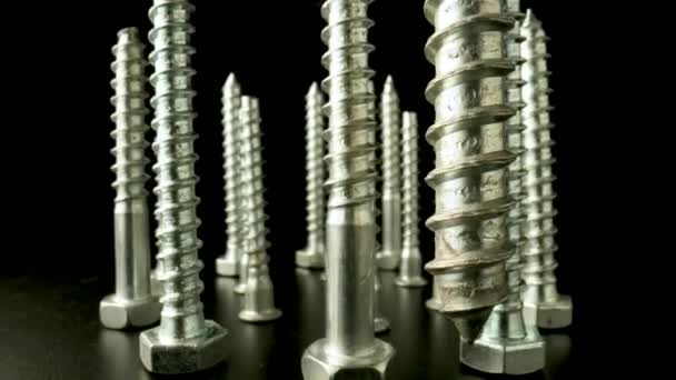 Screws, metal threaded bolts, fasteners rotating on isolated black background. Steel chrome anchor screws in a workshop or hardware shop. Super macro close up. Slow motion ready 59.97fps. — Stock Video