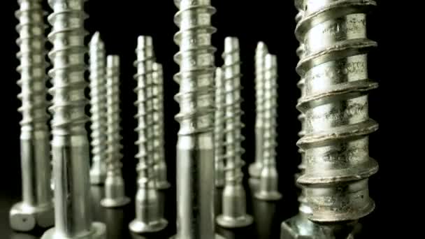 Screws, metal threaded bolts, fasteners rotating on isolated black background. Steel chrome anchor screws in a workshop or hardware shop. Super macro close up. Slow motion ready 59.97fps. — Stock Video