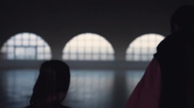 Bir kadın koçun arkasından ve bir kız öğrencinin koyu buz arenasında kayarak kayması. Artistik patinaj eğitimi. Yetenek çalışması, buz gösterisi koreografisi, eğitim. Ağır çekim. Kapat..
