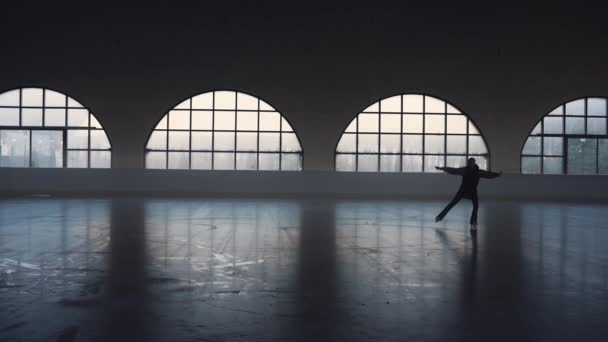 Mujer joven patinaje artístico patines entrenador en la arena de hielo oscuro. Silueta de patinadora femenina practicando las habilidades de rotación y salto. Entrenamiento de patinaje artístico. Practicando habilidades. Movimiento lento. — Vídeos de Stock