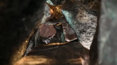Kamera, gri ve kahverengi granit taşlardan oluşan bir yığının içinde siyah bir arkaplana doğru hareket ediyor. Sert granit çakıl taşları, doğal dokusu ve kırık şekilleri var. Jeoloji. Taş geçidi. Yaklaş..