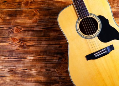 Ahşap arka planda klasik akustik gitar. Üzerinde fretboard, ses deliği ve tahta arka planda teller olan sarı akustik gitarın bir parçası. Müzik aleti. Kapat..