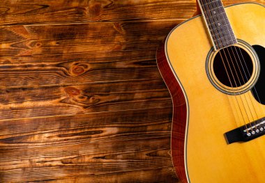 Ahşap arka planda klasik akustik gitar. Sarı telli müzik aleti tellerde akorlar ve melodiler çalmak için. Müzik okulu geçmişi, gitar çalmayı öğrenmek. Kapat..