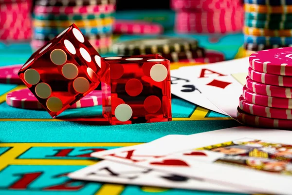 Kumarhanede kumar masasında poker oynamak için kırmızı zarlar, oyun kartları ve renkli fişler. Kumar, bahis, boş zaman kavramı. Poker, eğlence, risk, oyun yaşam tarzı. Kapat..