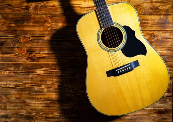 Ahşap arka planda klasik akustik gitar. Sarı telli müzik aleti tellerde akorlar ve melodiler çalmak için. Müzik okulu geçmişi, gitar çalmayı öğrenmek. Kapat..