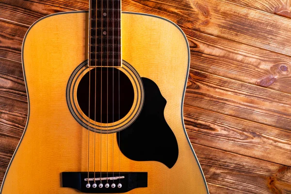 Része a test egy sárga akusztikus gitár fogólap, hang lyuk és húrok egy fa háttér. Vintage vonós hangszer közelről. Zene és művészet. — Stock Fotó