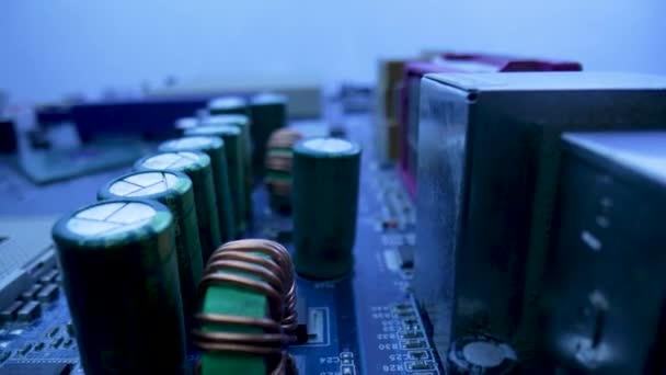 Computermotherboard-Mikroschaltung mit Chips, Steckplätzen, Kondensatoren und Prozessor im Blaulicht. Stromkreis des Mainboard-Computers schließen. Detail der elektronischen Komponenten auf dem PC-Motherboard. — Stockvideo