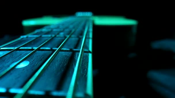 Fretboard of classical acoustic guitar against black background, illuminated by blue light. Brown wooden guitar neck with metal strings and frets extreme close up. Stringed musical instrument. — 비디오