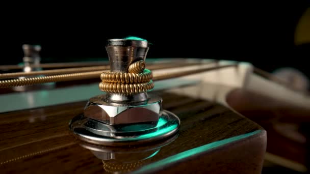 Ξύλινες κιθάρες headstock με μεταλλικά μανταλάκια και κορδόνι σε μαύρο φόντο. Pegs είναι στριμμένα για την ένταση και τη ρύθμιση του ήχου των χορδών. Ακουστική κιθάρα headstock close up μακροεντολή. — Αρχείο Βίντεο