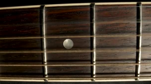 Neck of acoustic guitar. Details of wooden fretboard guitar. Classical guitar strings vibrate when playing a song. Close up on vintage acoustic guitar on the frets and metal strings. Music background. — стоковое видео