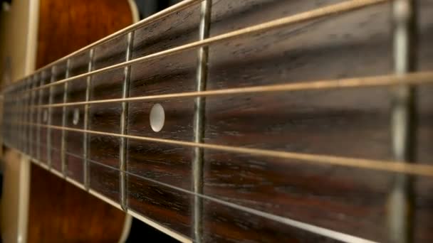Μοριοσανίδες ακουστικής κιθάρας. Κλασσικές χορδές κιθάρας δονούνται όταν παίζεις ένα τραγούδι. Καφέ ξύλινο λαιμό κιθάρας με κορδόνια και χαλινάρια ακραία από κοντά. Μέρος του σώματος μιας ξύλινης ακουστικής κιθάρας. — Αρχείο Βίντεο