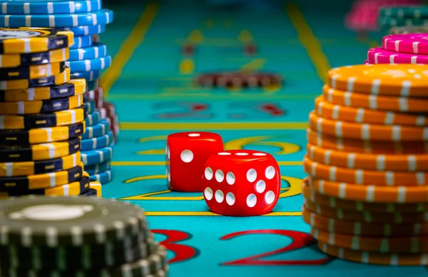 Röda tärningar och en uppsättning ljusa färgade pokermarker på ett grönt spelbord i ett kasino. Begreppet spel, vadslagning, fritid. Bakgrund till pokerspel. Underhållning, risk, spellivsstil. Närbild. — Stockfoto