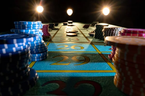 Set of colored chips for gambling in casino. Yellow, blue and pink gaming chips on poker table in the dark with backlight. Poker chips for betting close up. Concept of entertainment, gambling, wealth. — стоковое фото