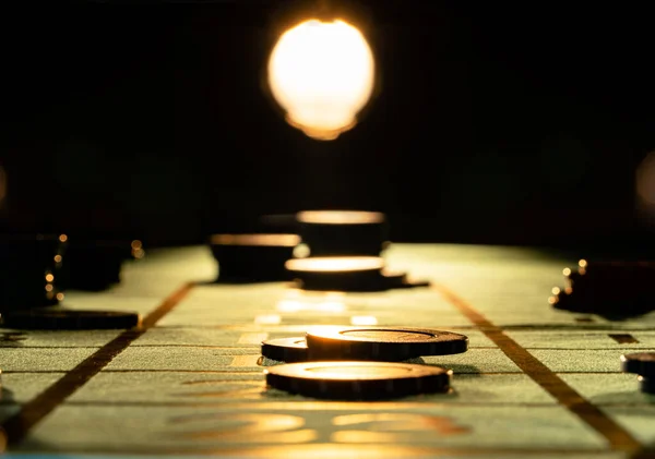 Πόκερ μάρκες στο τραπέζι τυχερών παιχνιδιών σε μαύρο φόντο με backlight. Τυχερά παιχνίδια μάρκες στοιχημάτων σε ένα σκοτεινό καζίνο κοντά. Η έννοια του παιχνιδιού, της ψυχαγωγίας, της επιτυχίας. — Φωτογραφία Αρχείου