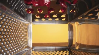 Sarı arka planda kırmızı pancar rendeleyen metal rendesinin iç görüntüsü. Öğütme, doğrama veya kesme için mutfak gereçleri. Paslanmaz mutfak aleti kapat. Restoran ya da kafe için mutfak geçmişi.