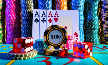 Kumarhanedeki kumar masasındaki renkli poker çiplerinin arka planında dört as var. İskambil kağıtları, poker kırmızı zarları ve 100 dolarlık fiş. Kumar, poker, yirmibir.