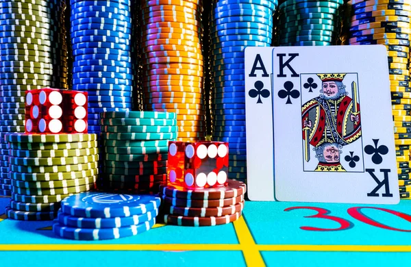 Kaarten spelen in een koning en aas lay-out op een achtergrond van chips en rode dobbelstenen met twee zessen op een pokertafel. Poker gezet op een blauwe speeltafel close-up. Casino gokken concept. — Stockfoto