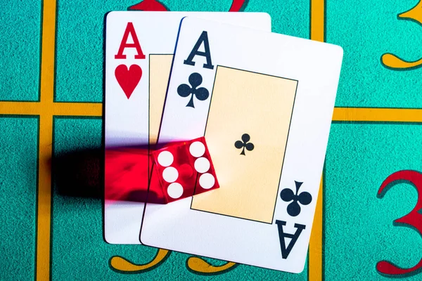 Een paar azen en rode dobbelstenen met de nummer zes liggend op een blauwe speeltafel in een casino. Spelkaarten en poker dobbelstenen close-up. Concept van casinospellen, gokken, poker, blackjack. — Stockfoto