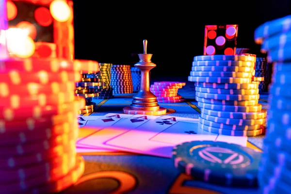 Un quad de cuatro ases, poner fichas y dados en la mesa de juego sobre fondo negro. Jugar a las cartas, fichas de póquer, fichas de crupier y dados rojos de cerca en la luz azul. Juego de azar, póquer, blackjack. —  Fotos de Stock