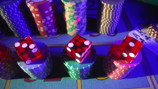 Die Kamera schwenkt über einen Spieltisch mit Karten, Chips, Würfeln und einem Dealer-Chip. Nahaufnahme eines Pokerspiels in einem Casino bei blauem Licht. Das Konzept des Glücksspiels, Wetten im Casino. — Stockvideo