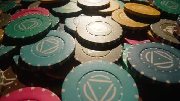 Heap of colored casino chips on a dark backlit table. Game chips for a casino close up. The concept of gambling and entertainment. Win, poker betting, roulette, blackjack. Camera movement. — стоковое видео