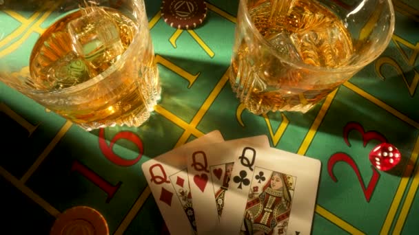 Widok na stół do gier w kasynie ze szklankami whisky i zestawem trzech pań. Zamknij ciemny stół pokerowy z alkoholem, kartami, kostkami i żetonami w kasynie. Zakłady kasynowe. — Wideo stockowe