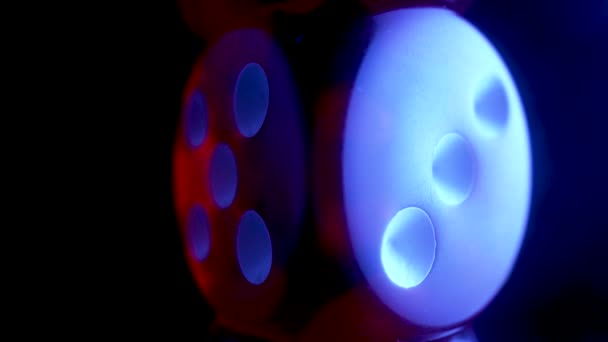 Red dice spinning on an isolated black background, illuminated by blue light. Red cube, craps close up. Gambling background. The concept of playing poker, entertainment. Online casino on the Internet. — стоковое видео
