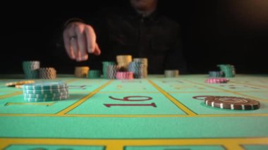 Tanımlanamayan erkek kumarbaz kumarhanede rulet masasında otururken bahis oynar. Kumarhane fişlerini riske atan bir adam. Kumar, rulet, poker, bahis, zenginlik konsepti. Kapat..