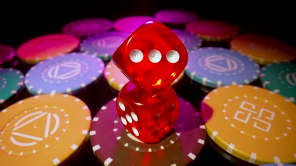 Red dice lying on a pile of casino chips spinning on a black background. Set for gambling, poker or blackjack close up. The concept of gambling, betting in the casino. Online casino on the Internet. — Vídeos de Stock