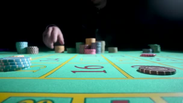 Unrecognizable male gambler makes bets while sitting at a roulette table in a casino. A man betting and risks all the casino chips. The concept of gambling, roulette, poker, bets, wealth. Close up. — Video