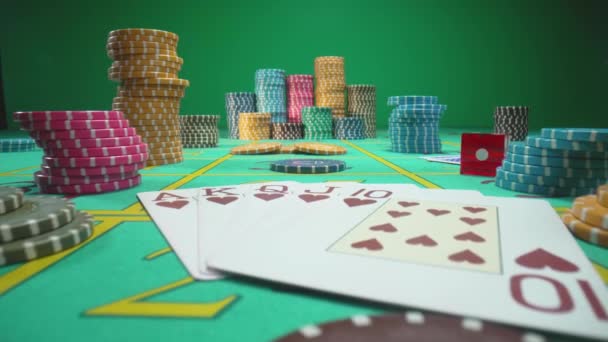緑の画面クロマキーの背景にカジノのチップ、カードやサイコロでゲームテーブルの上にカメラのパン。ロイヤルストリートフラッシュカードの組み合わせを閉じます。ギャンブル、ポーカー、カジノのブラックジャックのためのゲームテーブル — ストック動画