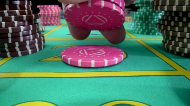 Camera pans over green gaming table with stacks of casino chips on black background. Mans hand lays pink chips on the table. Table for playing roulette or poker in a casino. Close up in slow motion. — Stock Video