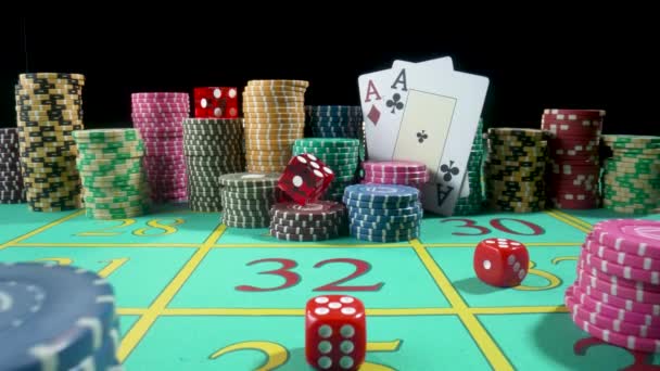 Σύνολο πολύχρωμων τσιπ, τραπουλόχαρτα και κόκκινα ζάρια σε ένα τραπέζι τυχερών παιχνιδιών για τυχερά παιχνίδια σε ένα καζίνο. Τα ζάρια που πέφτουν στο τραπέζι κλείνουν σε αργή κίνηση. Πόκερ που σε μαύρο φόντο. — Αρχείο Βίντεο