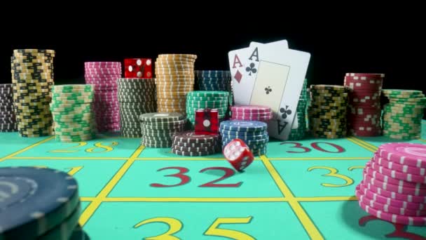 カジノでのギャンブルのためのゲームテーブルのカラフルなチップ、トランプ、赤いサイコロのセット。遅い動きでテーブルの上に落ちるダイス。黒の背景に設定されたポーカー. — ストック動画