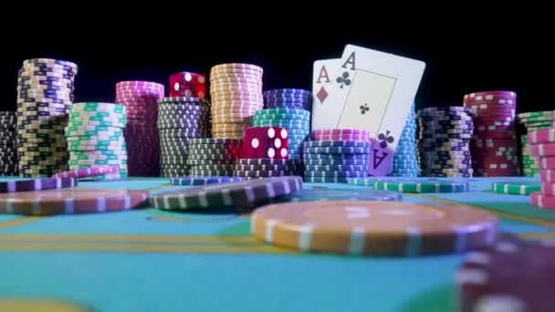 一套五颜六色的筹码，扑克牌和红色骰子放在赌桌上赌博。赌场的薯片掉在桌子上,慢吞吞地关上了.扑克设置在黑色背景上. — 图库视频影像
