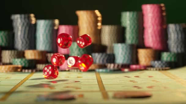 Czerwone kości spadające na stół do gier w kasynie na czarnym tle z rozmytymi żetonami. Kości, poker, blackjack. Pojęcie zakładów, rozrywki, wypoczynku. Zamknij się w zwolnionym tempie.. — Wideo stockowe
