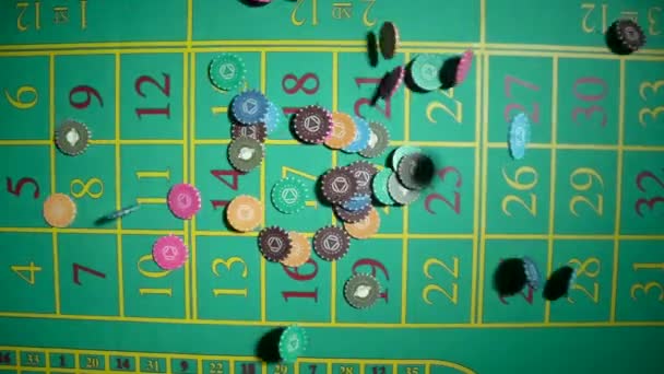 Bovenaanzicht van casino chips vallen en scatter close-up in slow motion op groene roulette tafel. Het concept van wedden, risico, winnen en entertainment in een gokclub. Gokken achtergrond. — Stockvideo