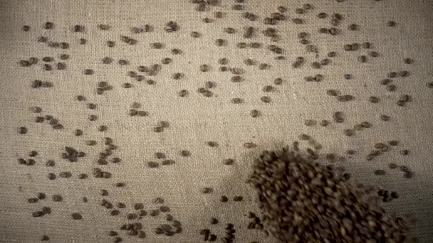 Top view of brown roasted coffee beans falling on a heap onto a burlap cloth. Coffee seeds spilling down in slow motion. Ingredient for preparing an invigorating morning drink. Close up. — Video Stock
