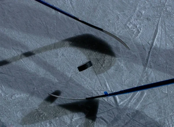 Ovanifrån av en ishall med en puck och pinnar. Hockeyspelare spelar pucken, kastar pucken i spelet på is. Hockeyträning, lagspel, rivalitet. Närbild. — Stockfoto