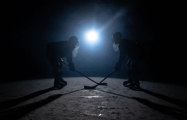 Silhuetter av två hockeyspelare som kolliderar med pinnar på isarenan. Rivalitet två manliga idrottare i uniform, hjälm och skridskor på hockeystadion. Lagspel, kollision, vintersport. — Stockfoto
