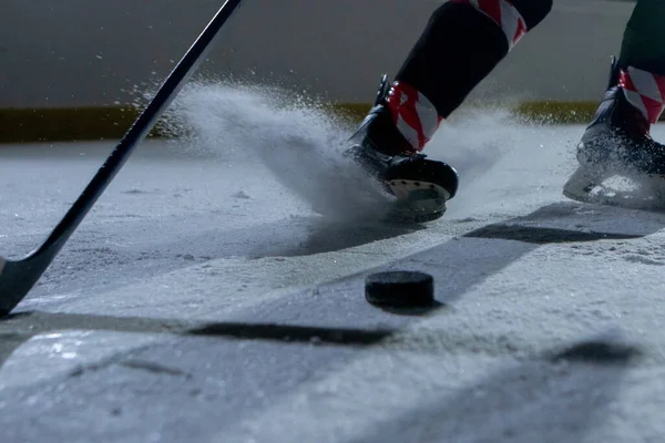 En hockeyspelare glider över arenan och träffar pucken med en hockeyklubba, skär isen i pulver. Matcha på ishallen. Hockey träning i en idrottsskola, slå pucken. Närbild. — Stockfoto